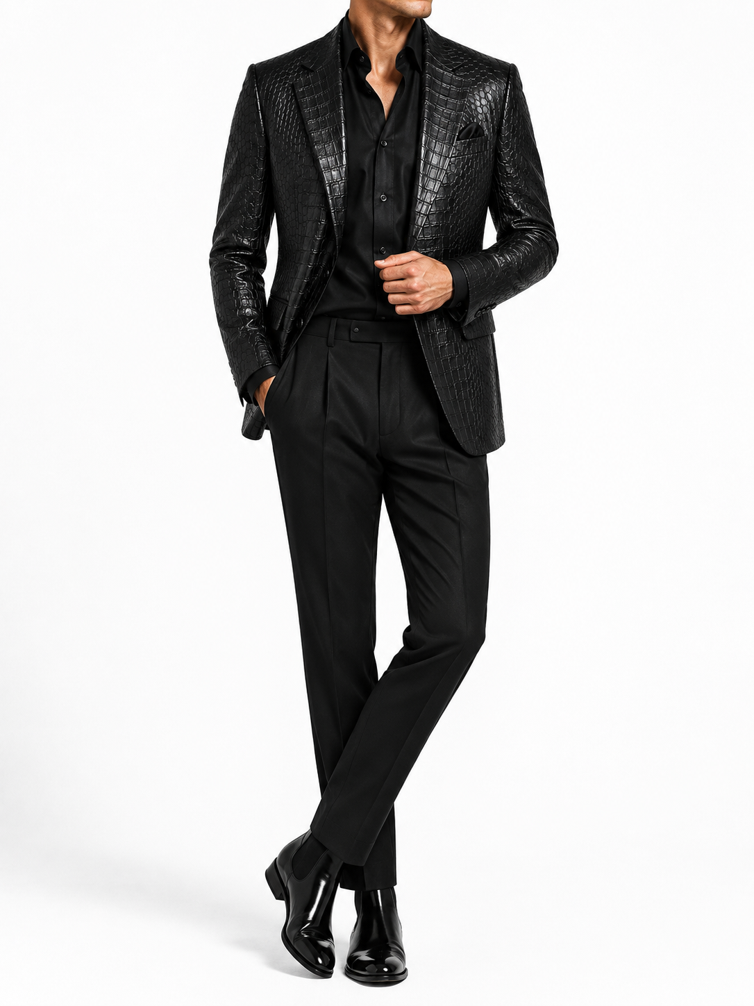 A man wearing a black textured leather blazer with a shawl collar, paired with a black shirt, black trousers, and black leather shoes, photographed against a solid white studio background.